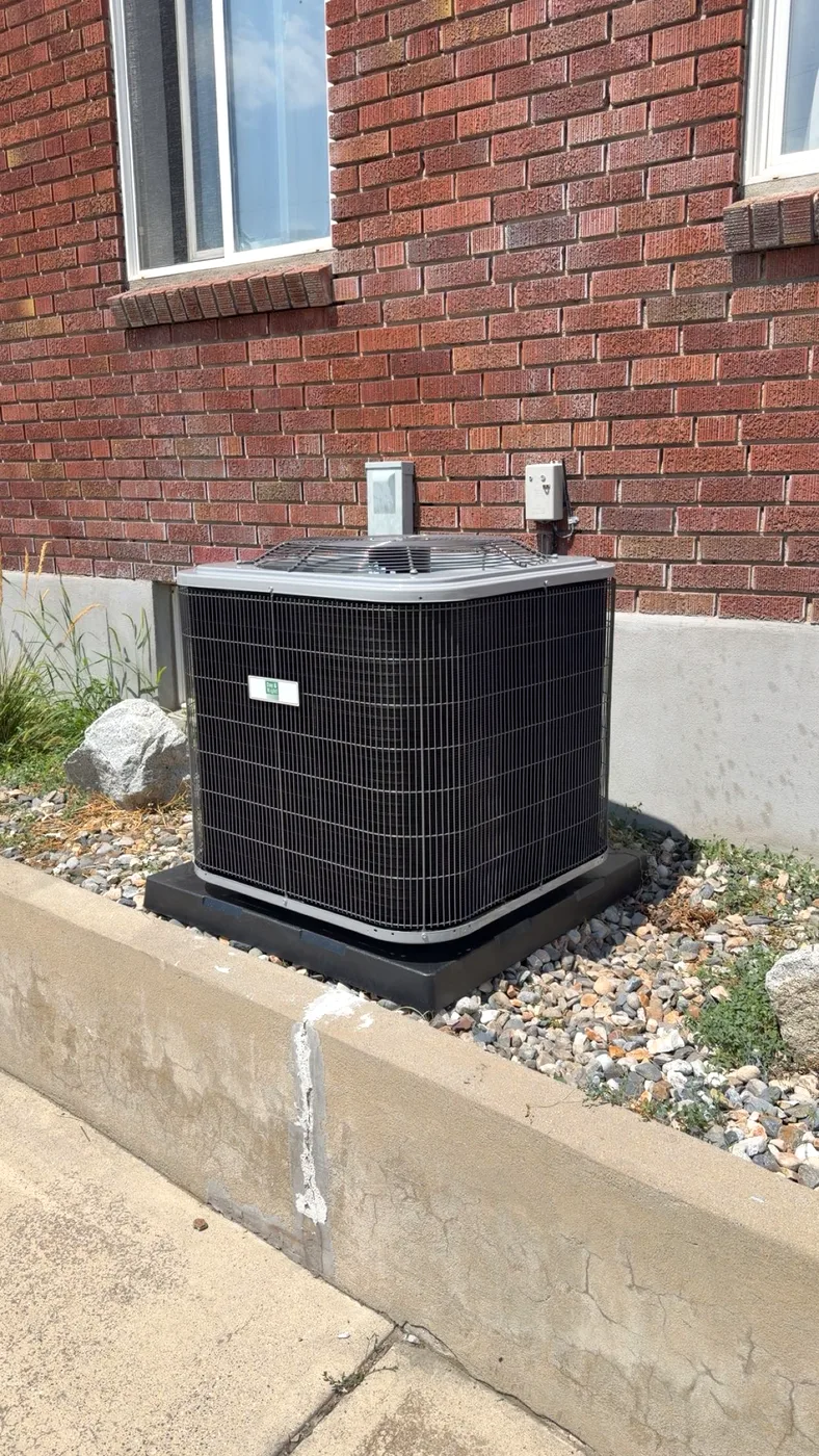 Residential AC condenser installed against a brick Utah home by Honest Heating & Cooling